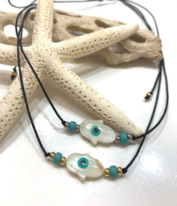 Collar confeccionado a mano con un "charms" en nácar con una mano de fatima montada en hilo de nylon ajustable. Excelente joyería que no se despinta y tiene un bello estilo moderno y fino. Se puede utilizar para uso diario.